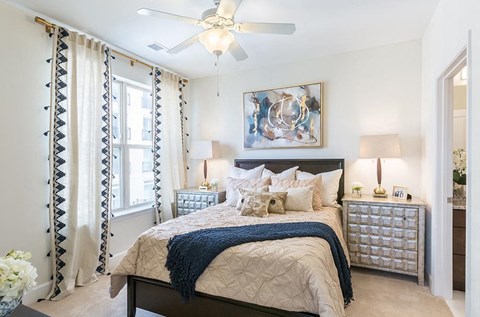 A bedroom with a large bed and a ceiling fan.