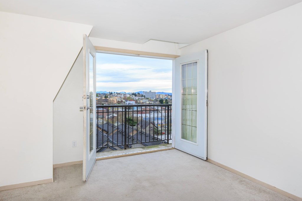 A view of a city from a balcony through a glass door.