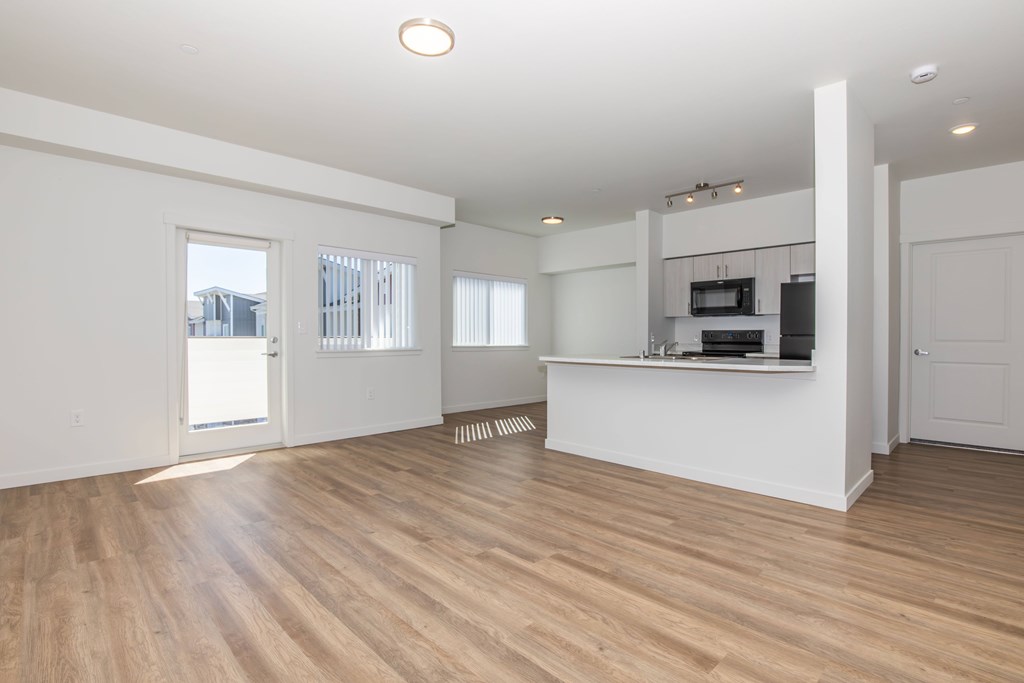 A spacious room with wooden floors and white walls.