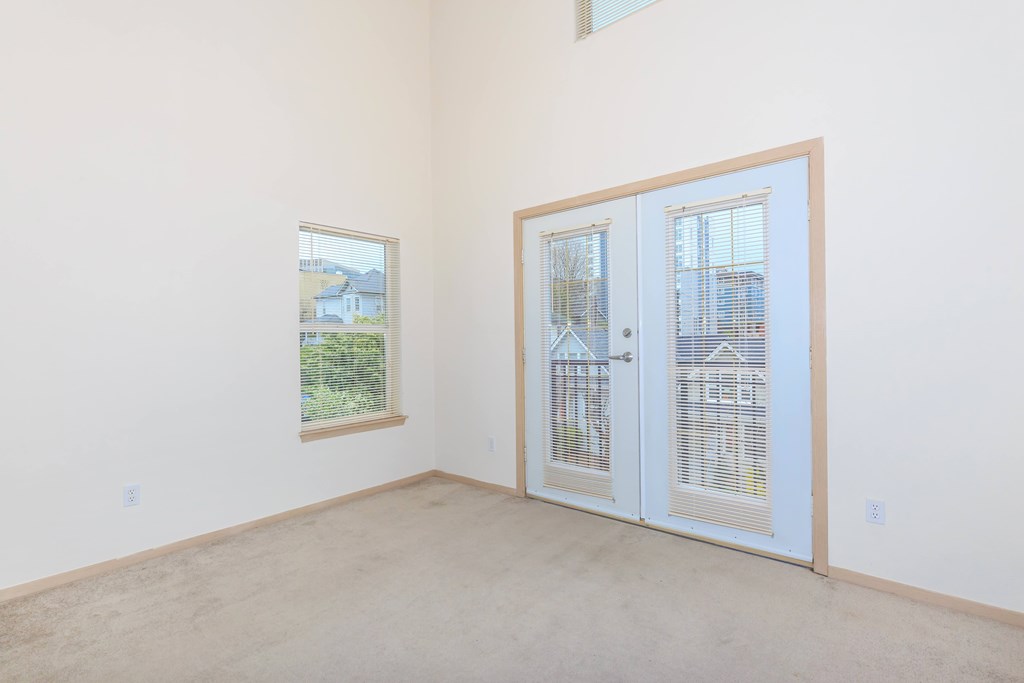 A room with a white door and a window with a view of a house.
