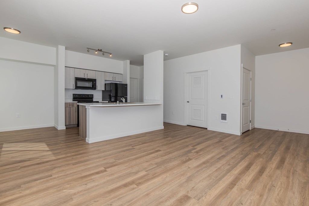 A kitchen with a white countertop and wooden flooring.