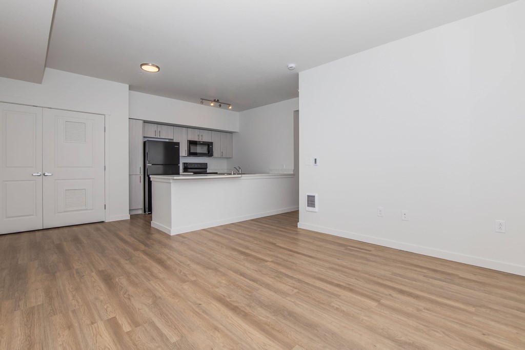 A kitchen with a white counter and wooden floors.