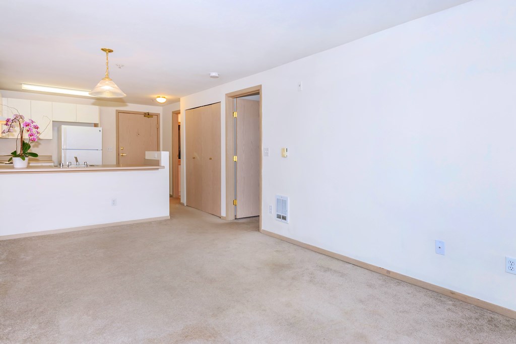 A kitchen with a sink, a refrigerator, and a counter with a vase of flowers on it.