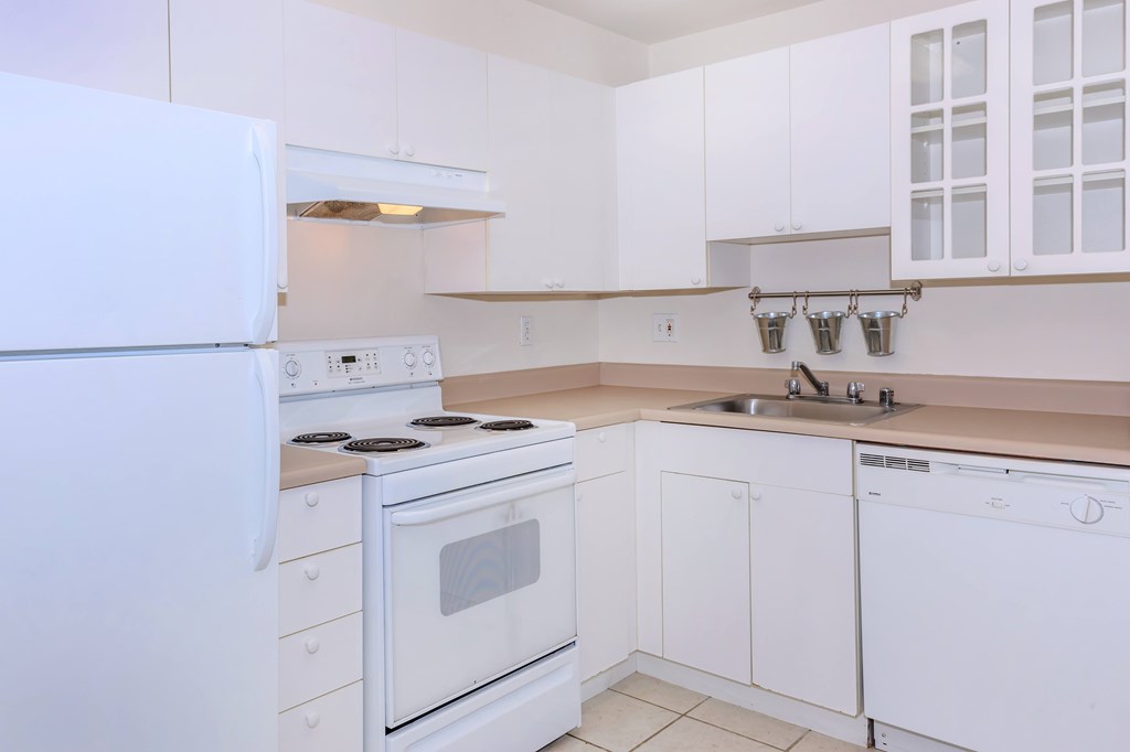 A white kitchen with a refrigerator, stove, and dishwasher.
