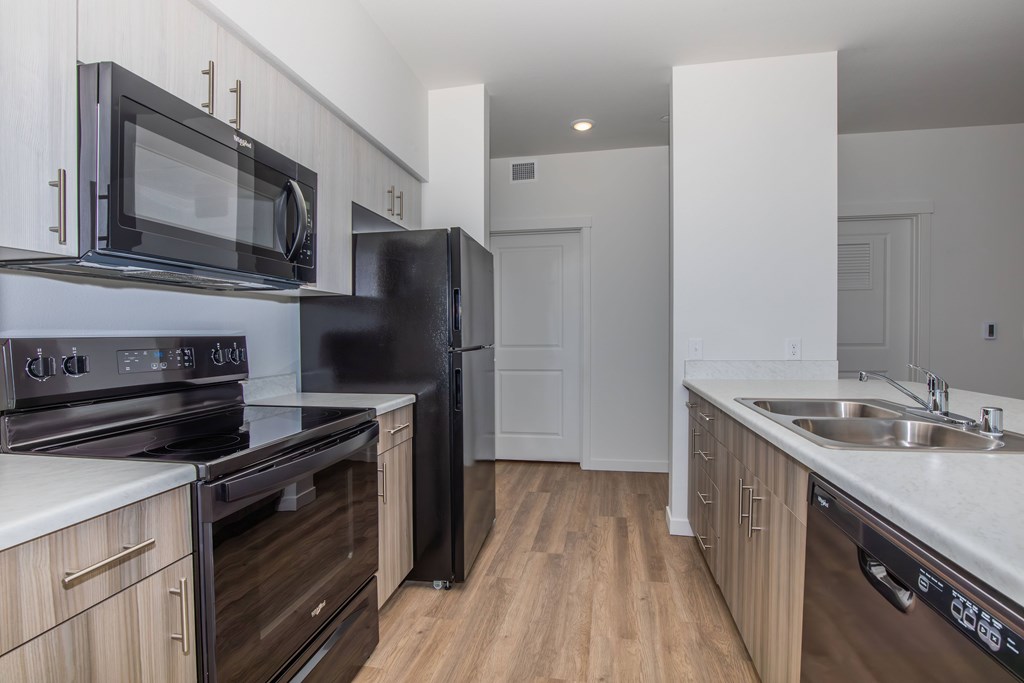 A kitchen with black appliances and wooden cabinets.