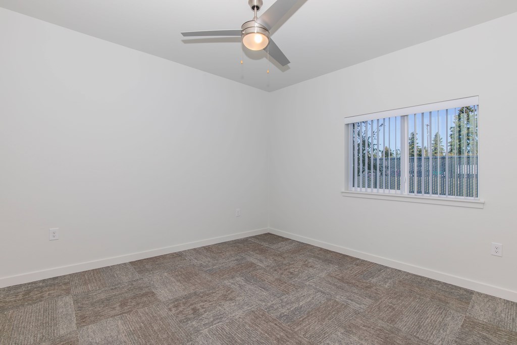 A room with a ceiling fan and a window with blinds.