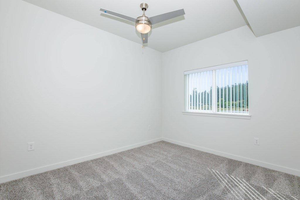 A room with a ceiling fan and a window with blinds.