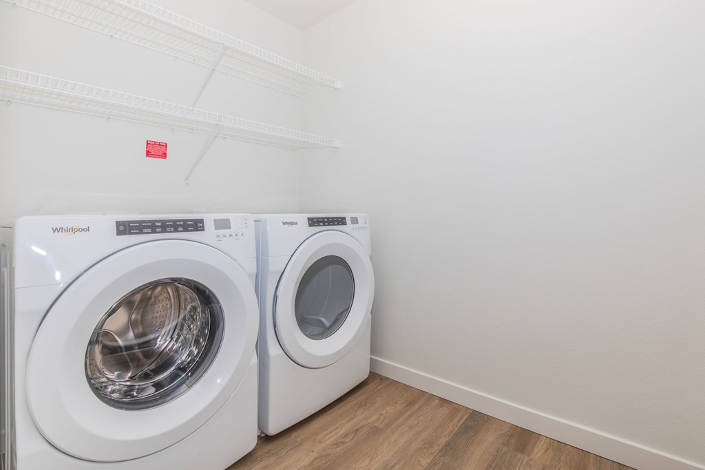 Two white Whirlpool washing machines in a laundry room.