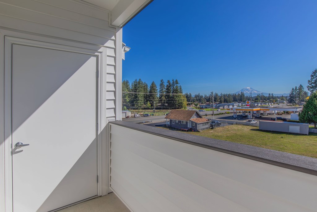 A view from a window of a house with a white door and a mountain in the distance.