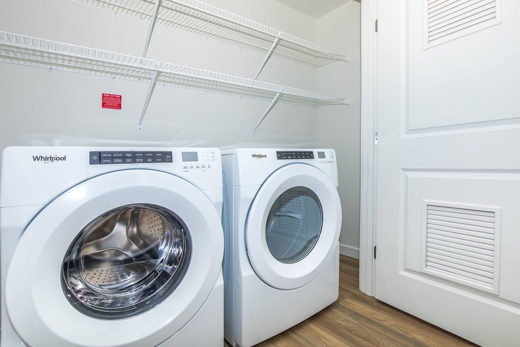Two white Whirlpool washing machines in a laundry room.