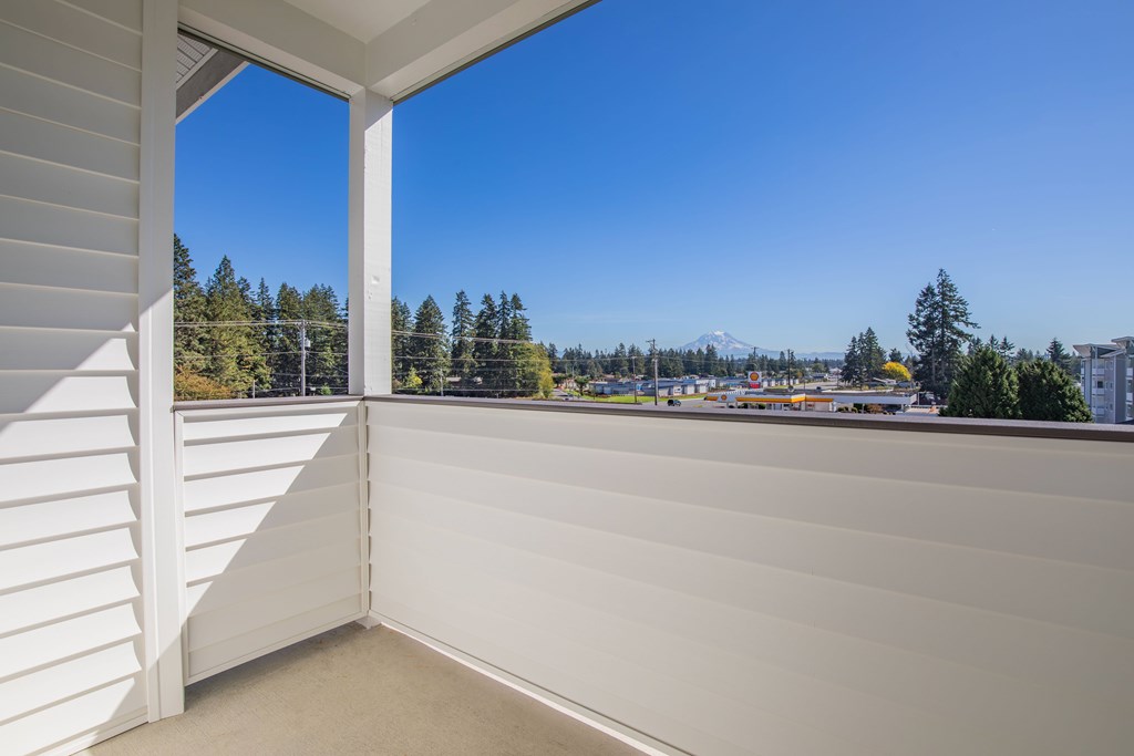 A balcony with a view of a parking lot and trees.