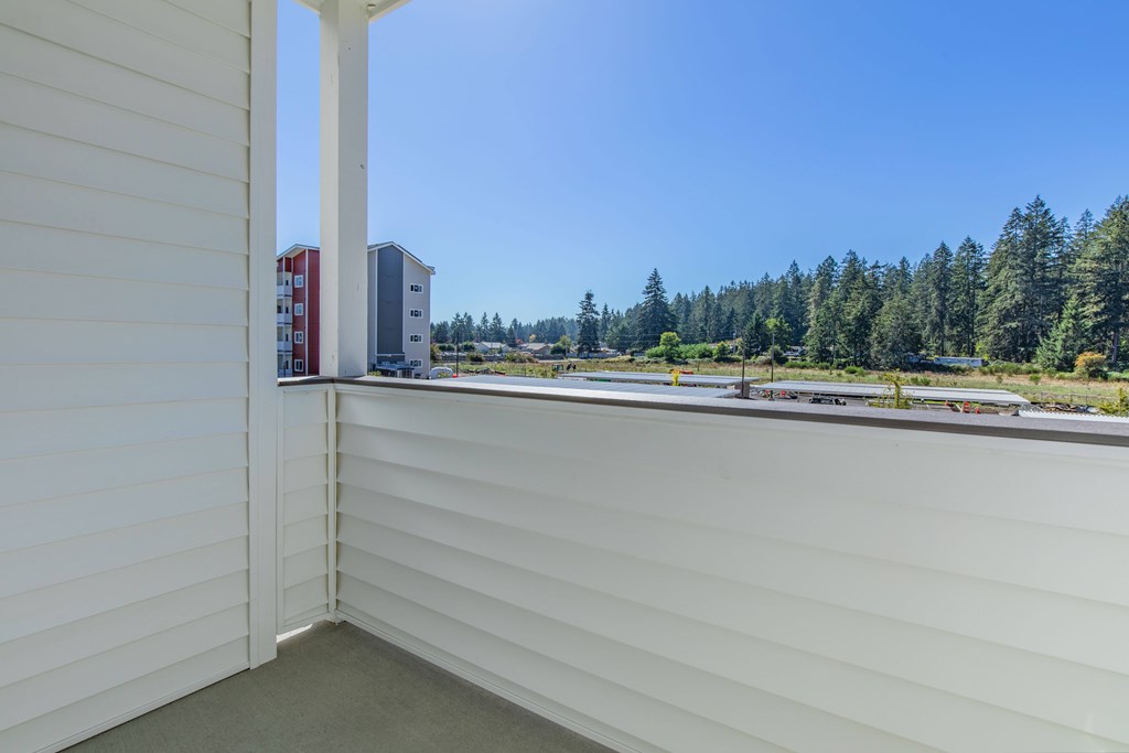 A view from a window of a white building with a red and white building in the distance.