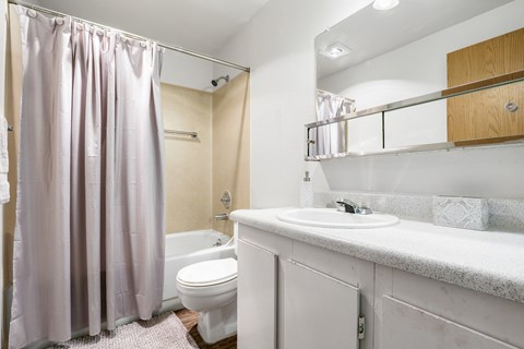 A white toilet sits under a shower curtain in a bathroom.