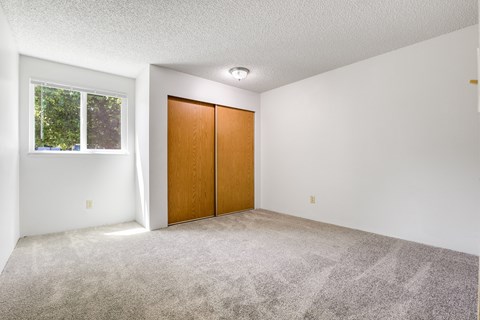 A room with a carpeted floor, a wooden door, and a window.