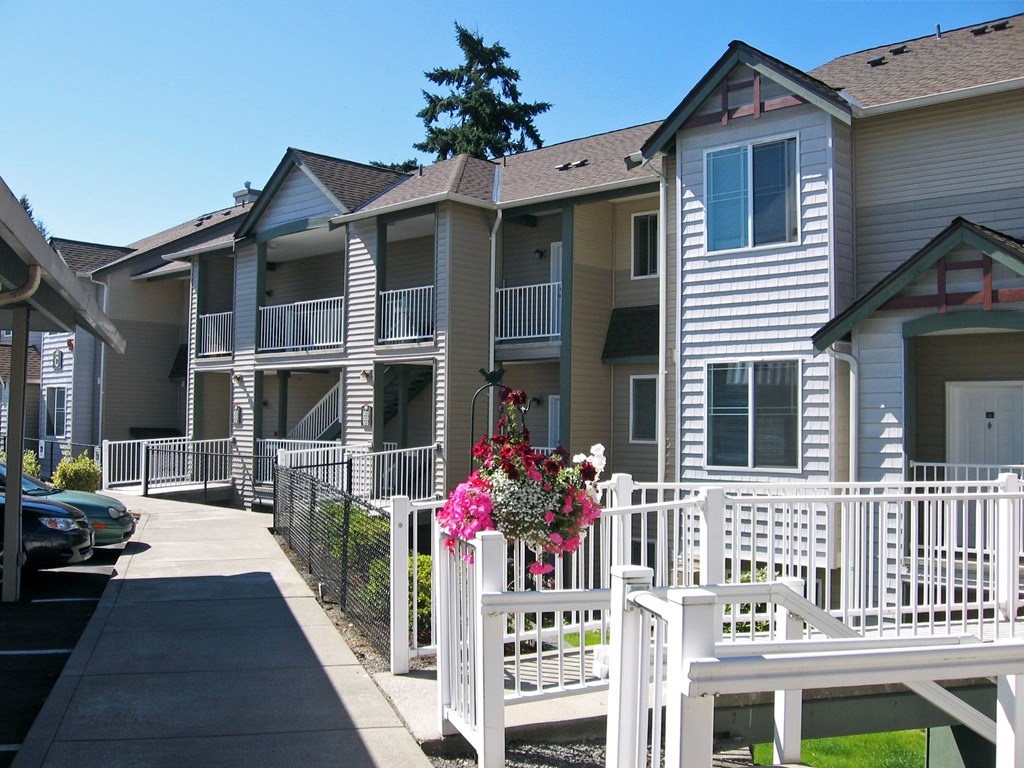 A white picket fence with a bench and flowers on it.