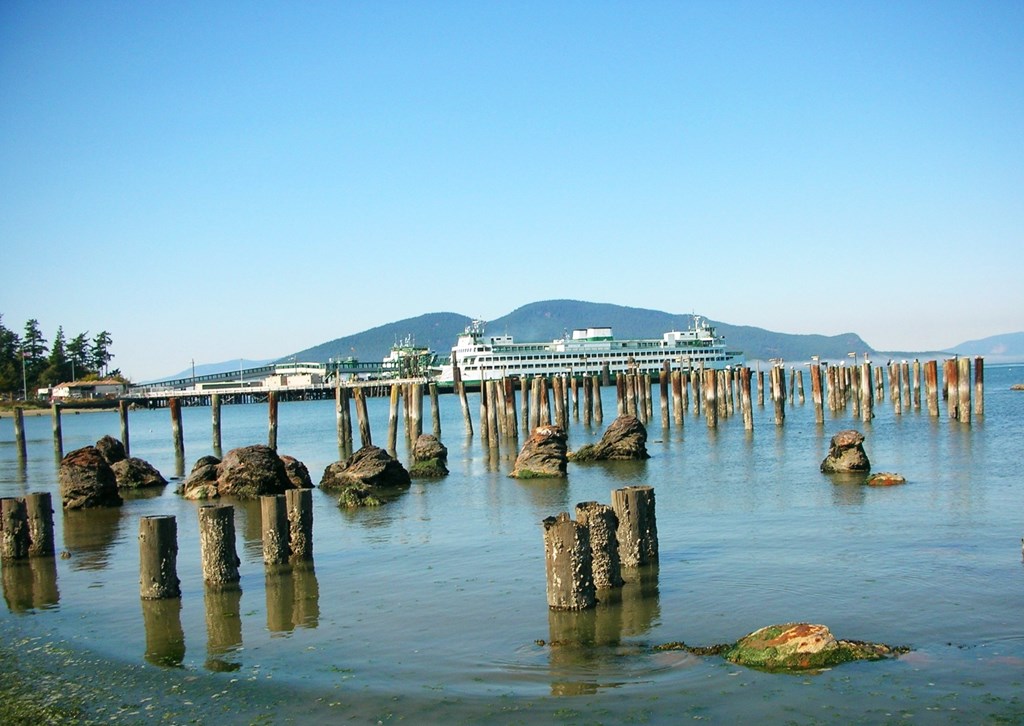 A pier extends into a calm body of water with a mountain in the distance.