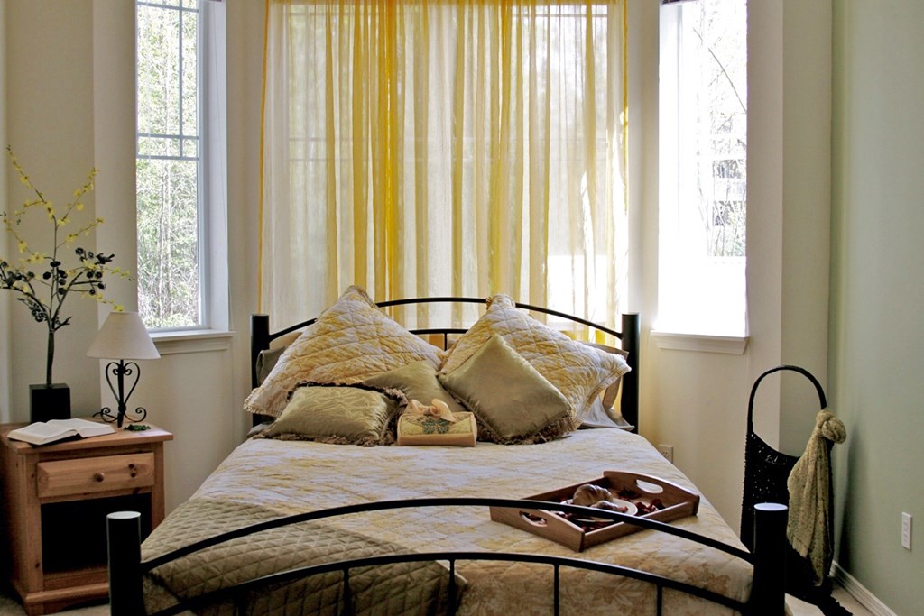 A bed with a yellow comforter and a black headboard.