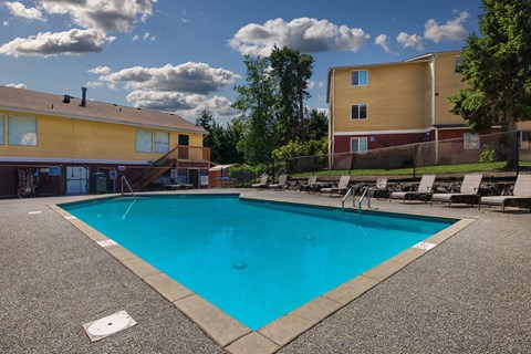 A swimming pool surrounded by a concrete floor and a fence.