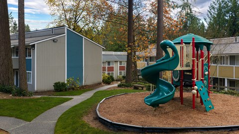 A playground with a green slide and red and white toy.