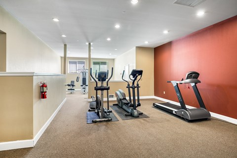 A well-lit gym with treadmills, elliptical machines, and other exercise equipment.