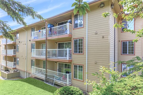 Apartment building with balconies and greenery in front.