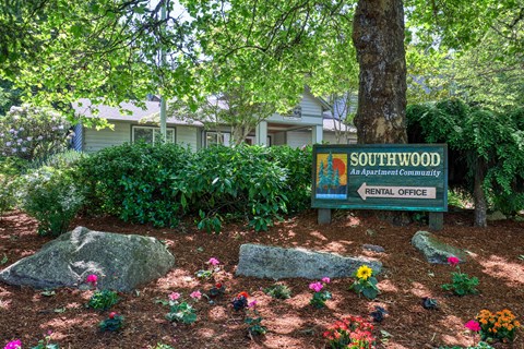 A sign for Southwood Apartment Community Rental Office is in front of a tree.