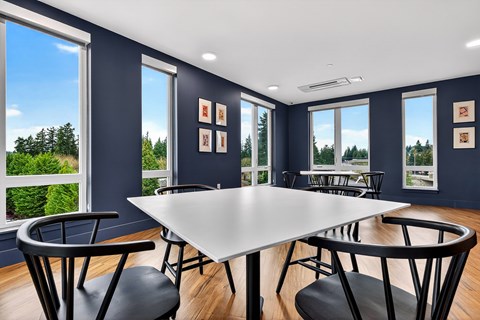 A dining room with a white table and black chairs.