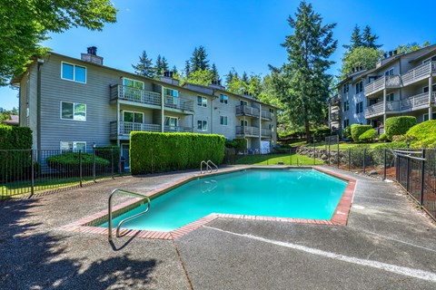 A swimming pool surrounded by a fence and apartment buildings.