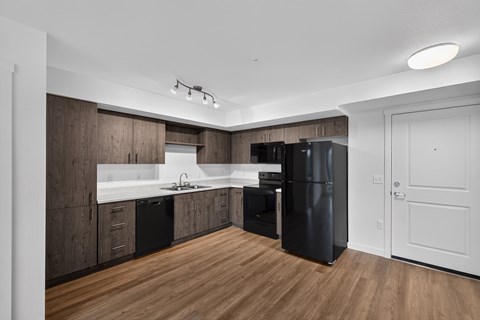 A modern kitchen with dark wood cabinets and a black refrigerator.