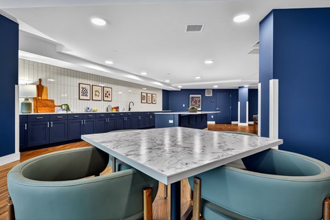 A modern kitchen with a marble table and teal chairs.