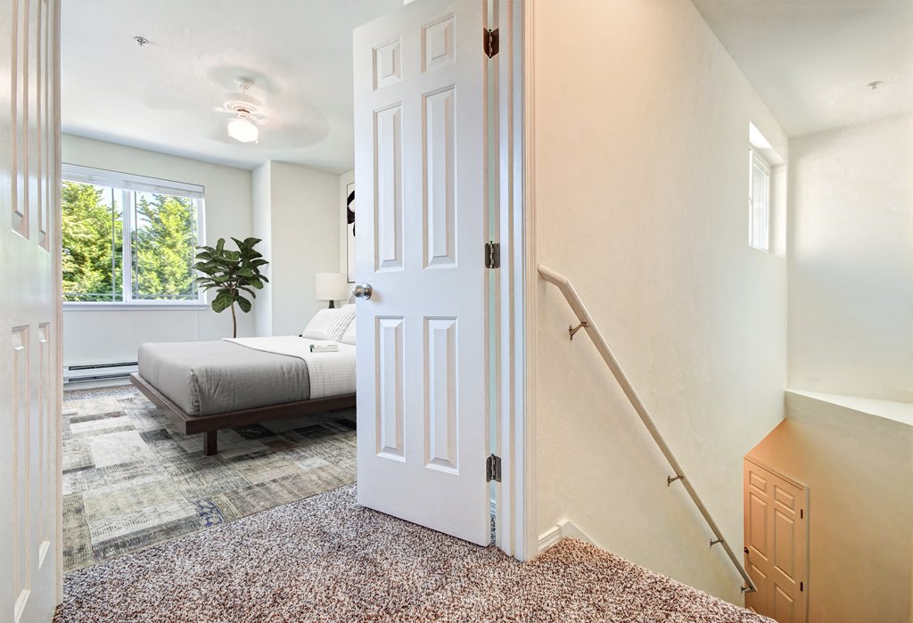 A white door is open in a room with a bed and a plant.