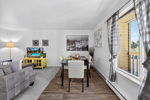A dining room with a table set for two and a couch.