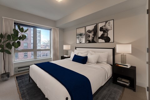 A bedroom with a large bed and a window overlooking a city.
