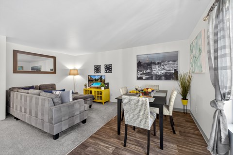 A grey couch sits in a living room with a dining table and chairs.