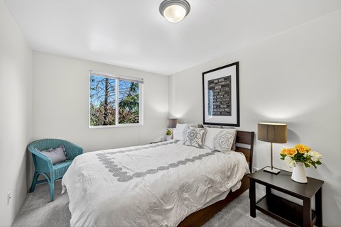 A bedroom with a large bed and a blue chair.