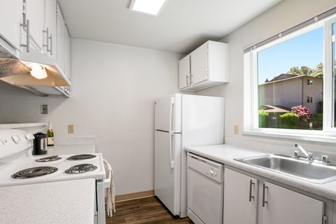 A white kitchen with a stove, refrigerator, and dishwasher.