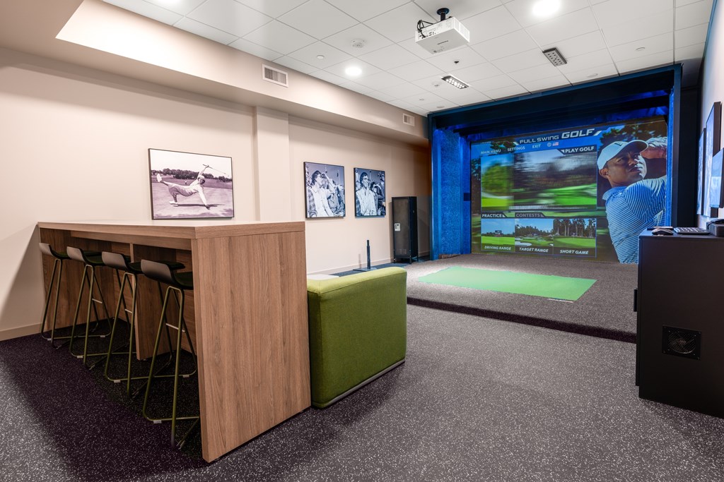 A room with a golf simulator and a green screen.