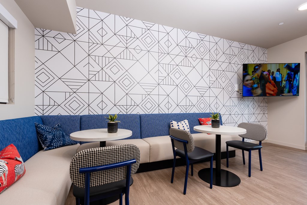 A white table with a plant on it sits in front of a wall with a geometric pattern.
