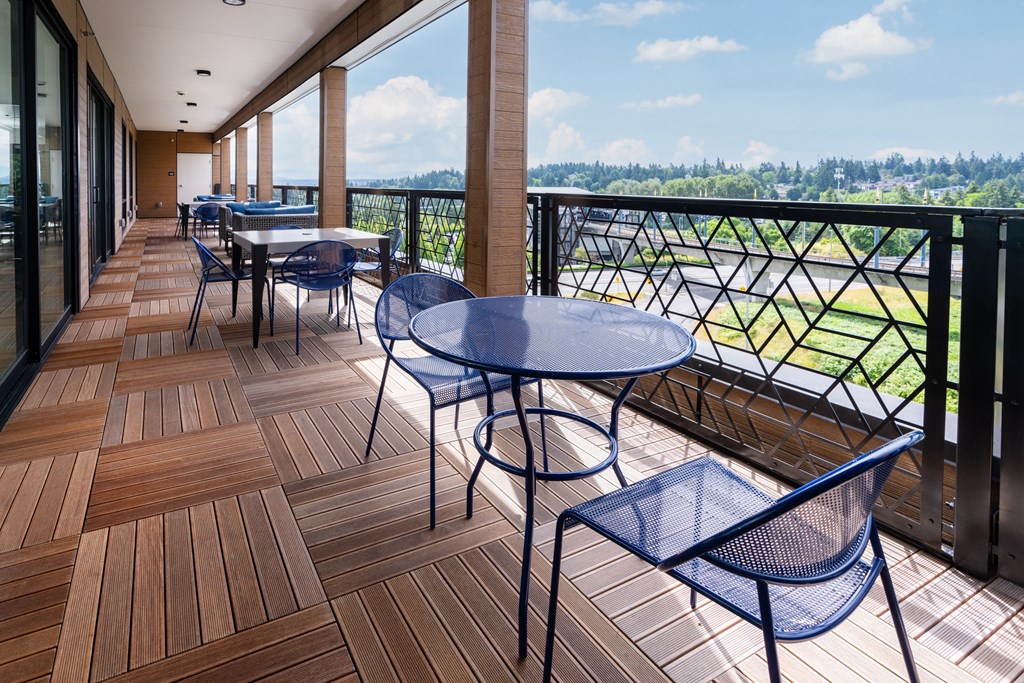 A balcony with a table and chairs overlooking a field.
