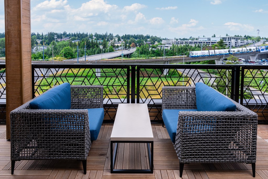 A balcony with a table and two chairs with a view of a highway and buildings.