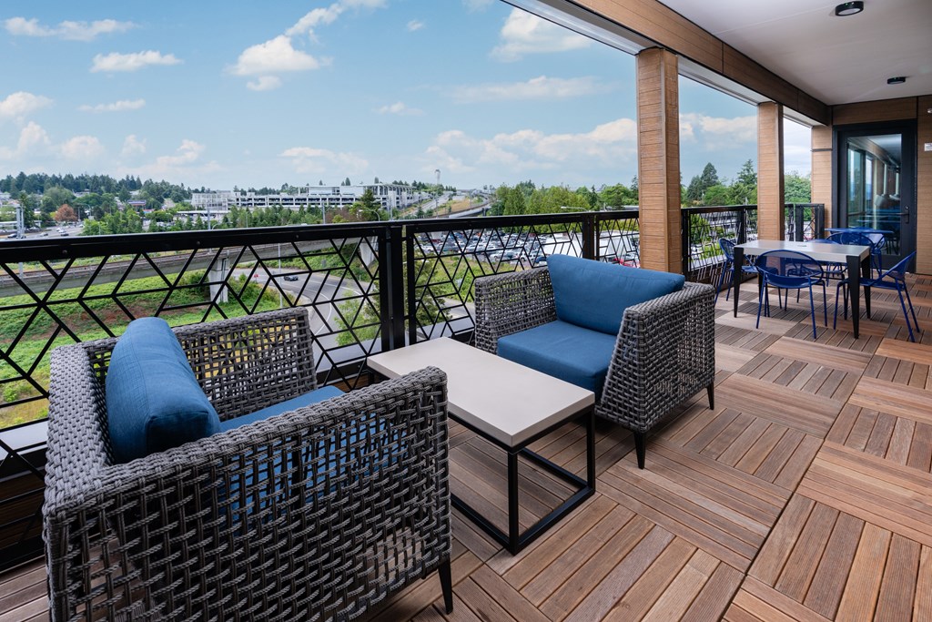 A balcony with a table and chairs overlooking a cityscape.