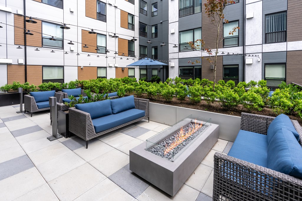A patio with a fire pit and blue couches.