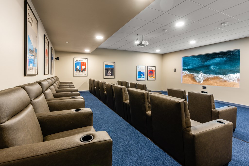 A row of brown leather seats in a room with a large painting on the wall.