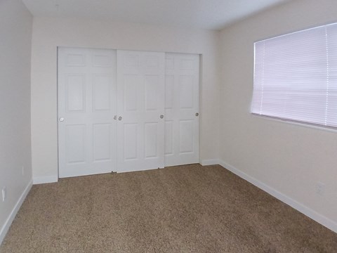 A room with white doors and carpeted floor.
