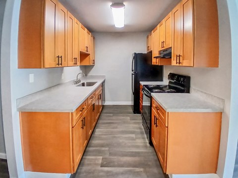 A kitchen with wooden cabinets and black appliances.
