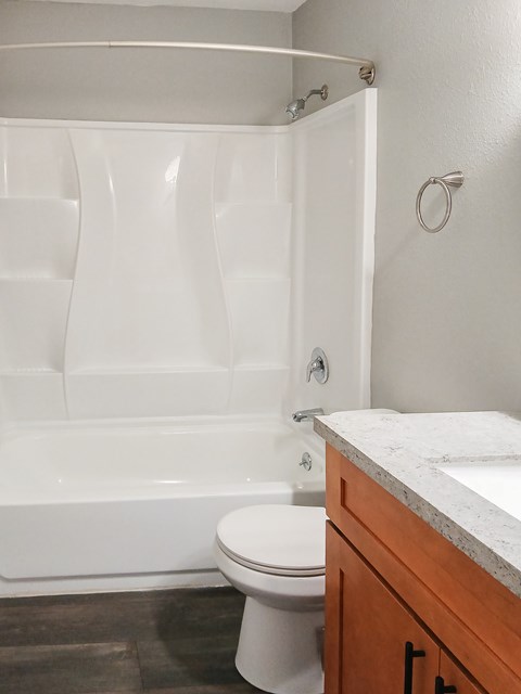 A white toilet sits next to a white bathtub in a bathroom.