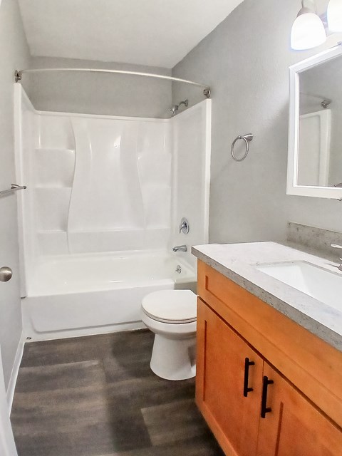 A white toilet sits in a bathroom next to a bathtub and a sink.