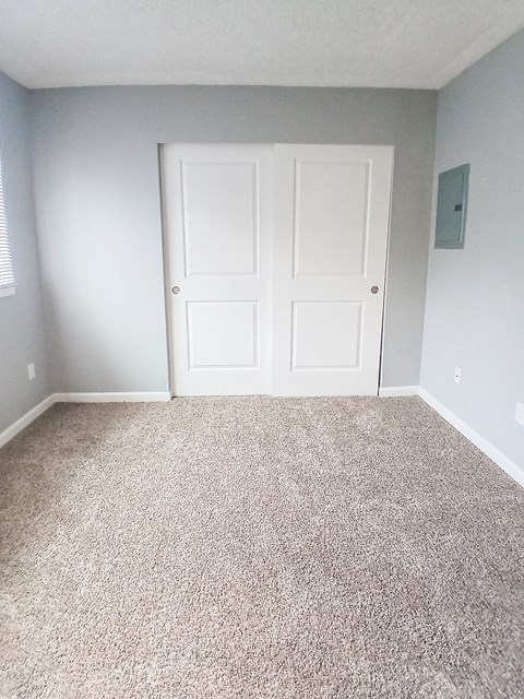 A room with a white door and carpeted floor.