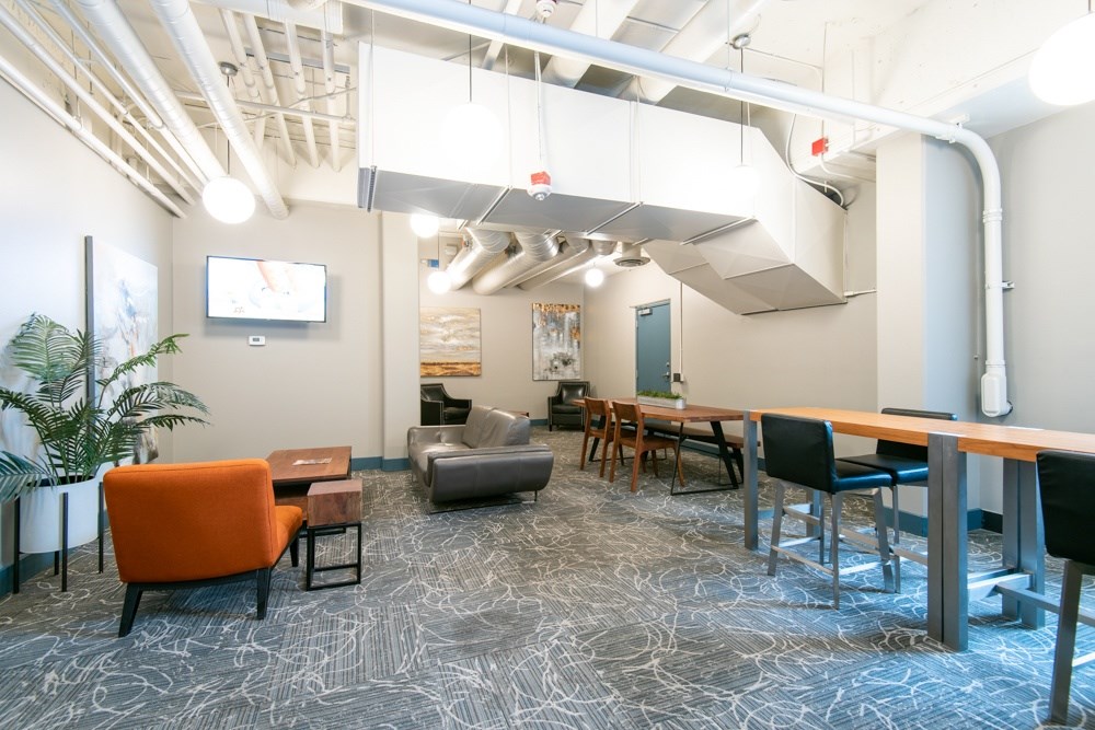 A modern office space with a patterned carpet and a mix of orange and black furniture.