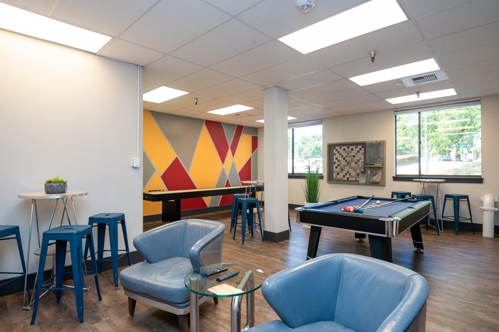 A room with a pool table and a bar area.